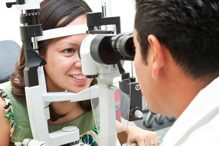 Woman in green dress in an eye exam with his eye doctor