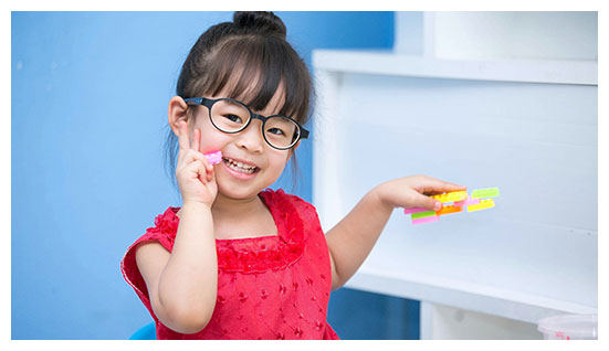Kid in pink dress wearing her eyeglasses